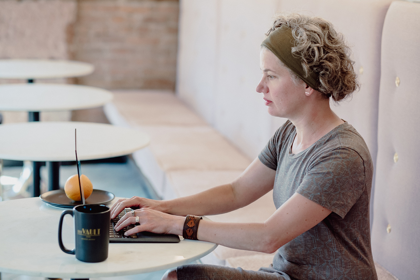 woman sitting at a cafe table working on her latop with a mug of coffee